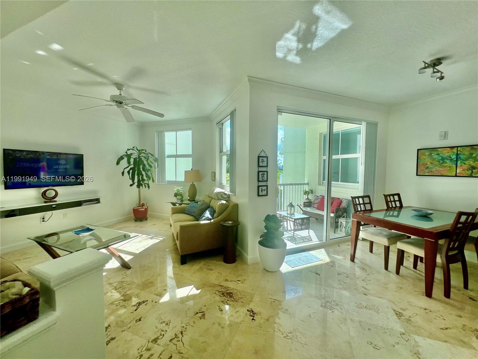 A bright living and dining area features marble floors, a ceiling fan, and a balcony — 9172 Collins Ave # 305, Surfside FL 33154, SURFSIDE, FL