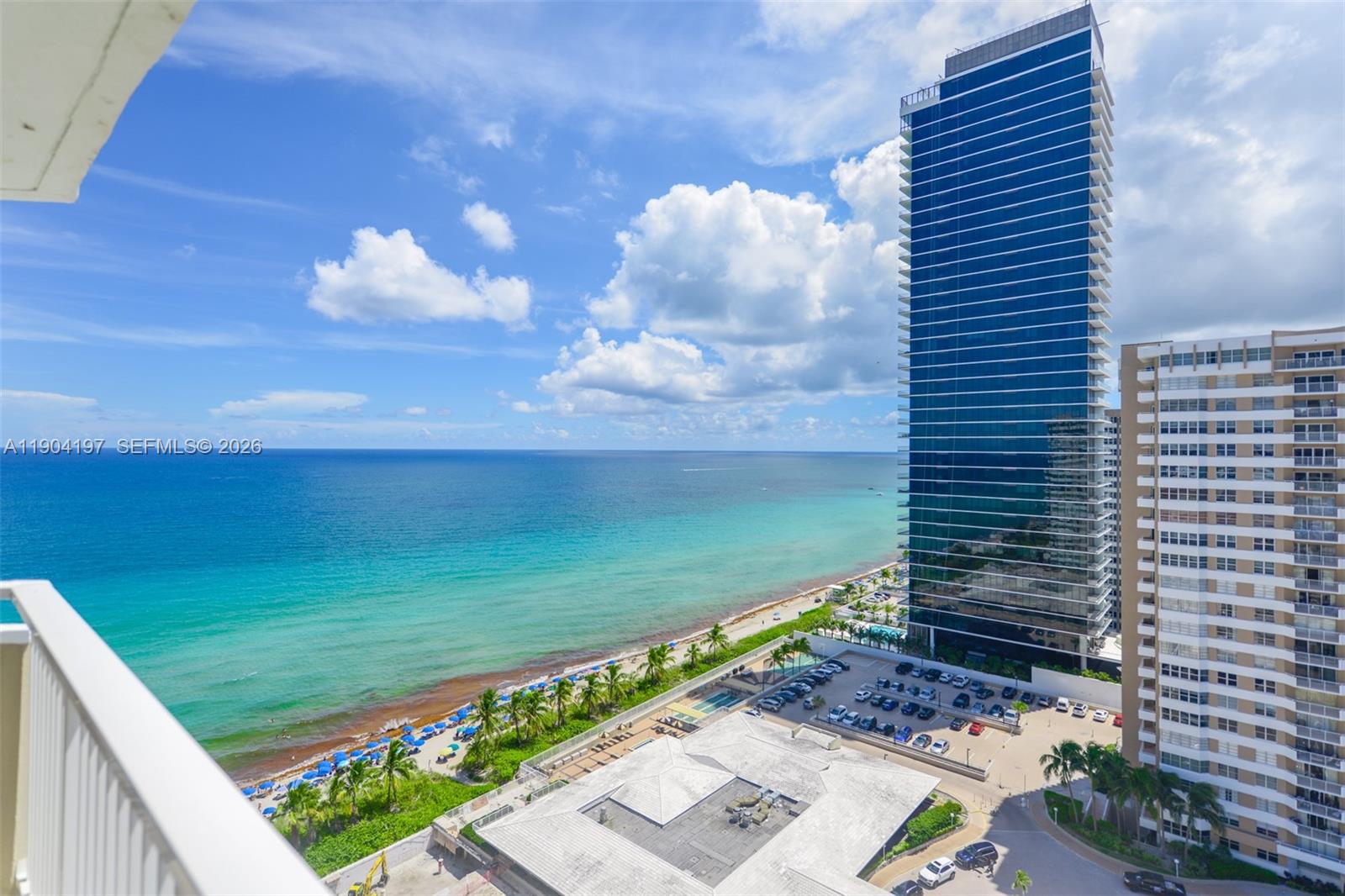 A high-angle view shows a beach, a modern glass skyscraper, and a parking lot — 1950 S Ocean Dr # 19A, Hallandale Beach FL 33009, HALLANDALE BEACH, FL