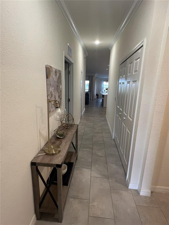 A long hallway with tile flooring, a console table, and a white closet door — 5674 PALMER CIRCLE UNIT 203, BRADENTON, FL