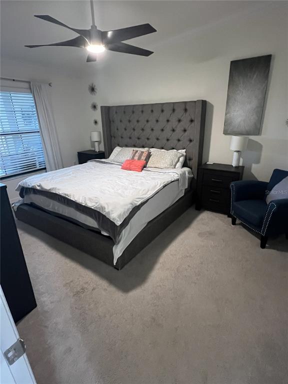 A bedroom features a tufted gray headboard, a ceiling fan, and a blue armchair — 5674 PALMER CIRCLE UNIT 203, BRADENTON, FL