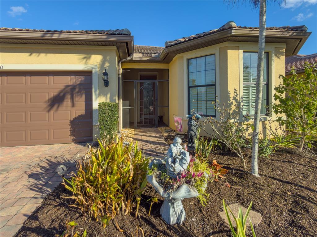 A single-story house with a brown tile roof, tan stucco walls, and a paved driveway — 19770 QUISTO STREET, VENICE, FL