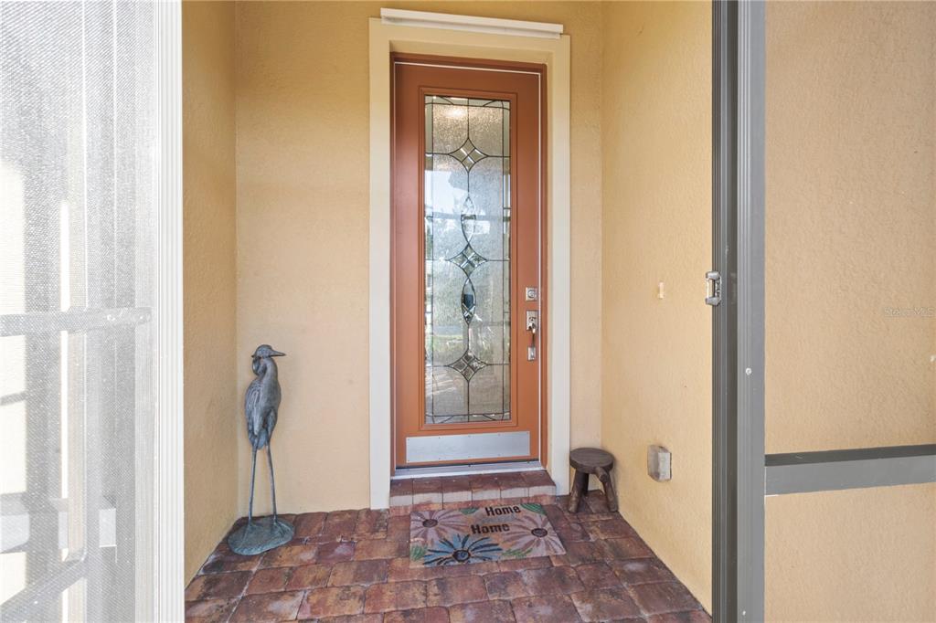 A front entryway features a decorative glass-paneled door, a heron statue, and a floral doormat — 19770 QUISTO STREET, VENICE, FL