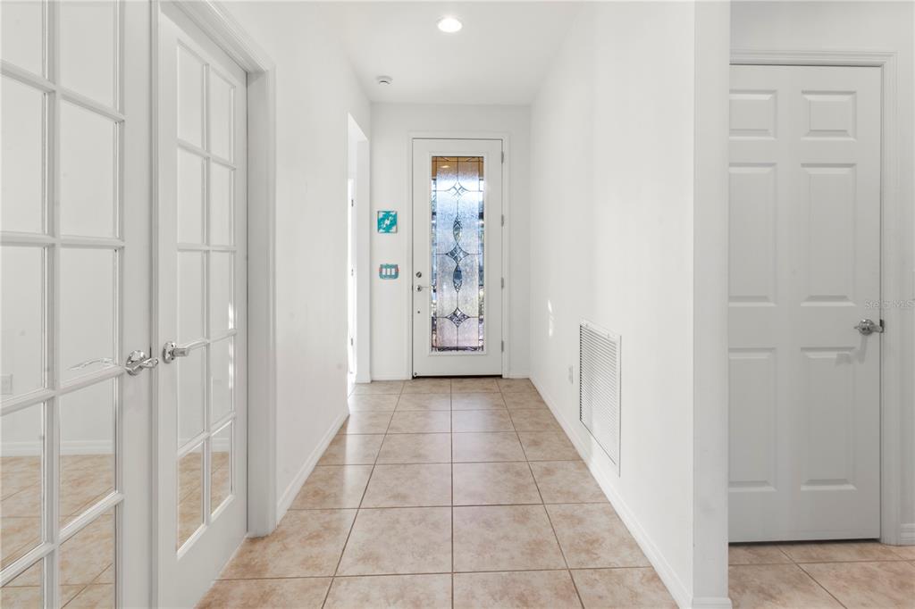 A bright entryway features tiled flooring, white walls, a glass-paneled front door, and French doors — 19770 QUISTO STREET, VENICE, FL