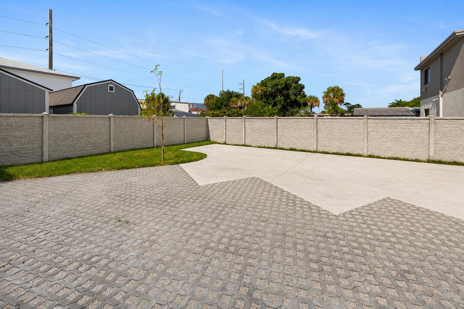 A paved backyard features a concrete patio, a small patch of grass, and a concrete fence — 1181 NW 66th Street # 1181, Miami FL 33150, MIAMI, FL