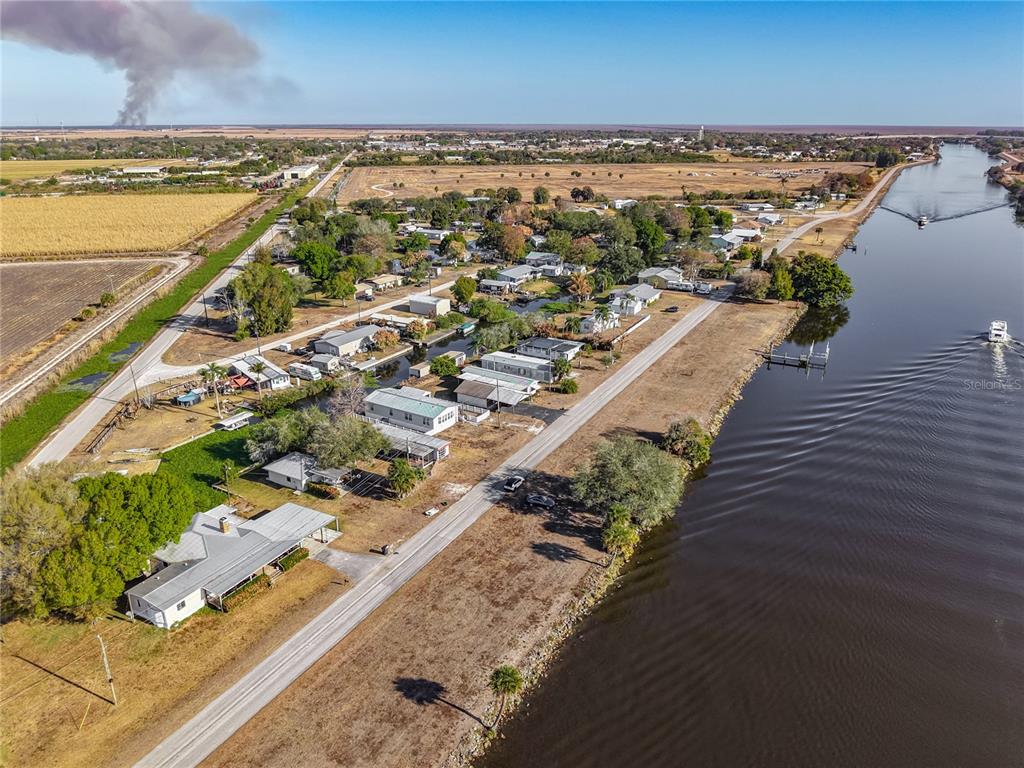 An aerial view shows a residential street running alongside a canal with boats — 1824 RIVERSIDE DRIVE, MOORE HAVEN, FL