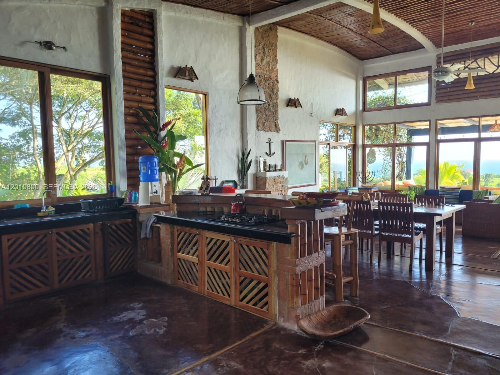 A rustic kitchen and dining area features wooden cabinetry, stone accents, and large windows — San Jose San Jose, FL