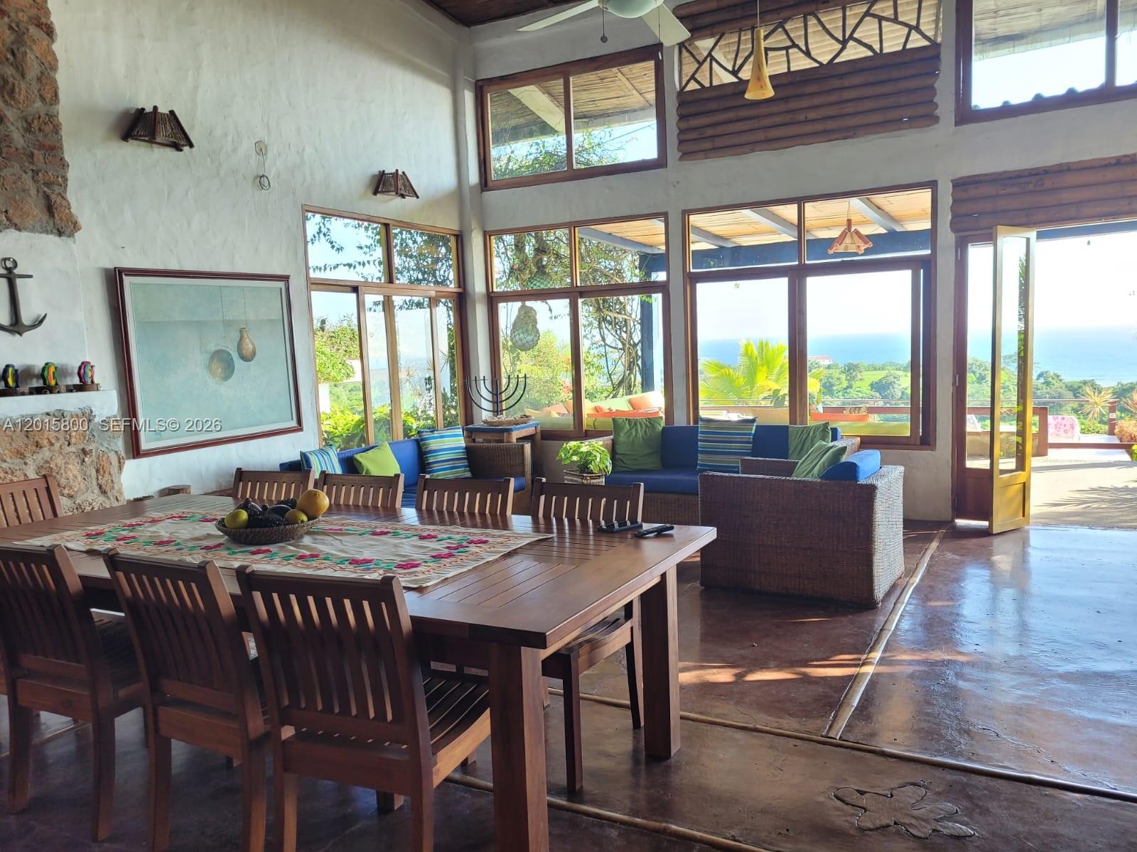 A spacious living and dining area features wooden furniture, large windows, and ocean views — San Jose San Jose, FL