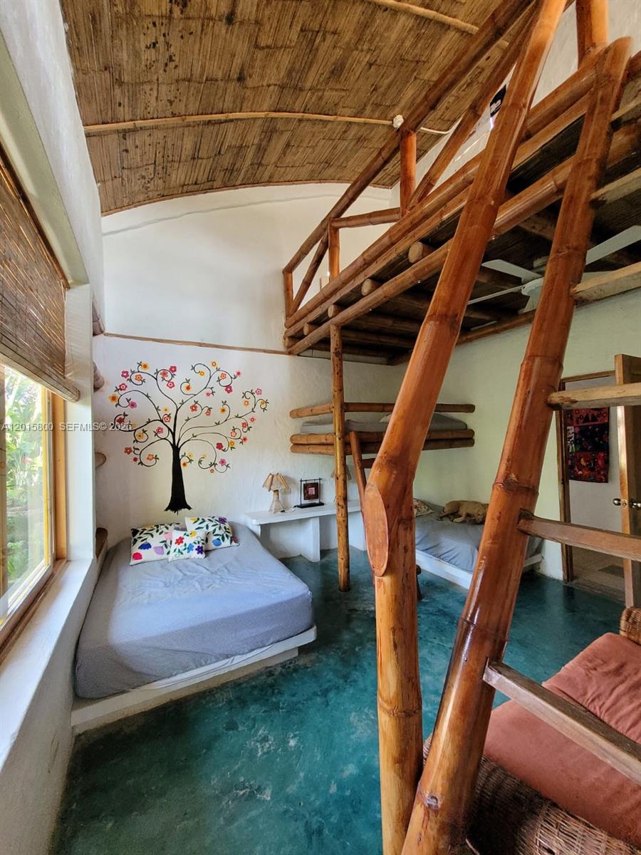 A bedroom features a bamboo loft bed, a lower bed, and a painted tree mural — San Jose San Jose, FL