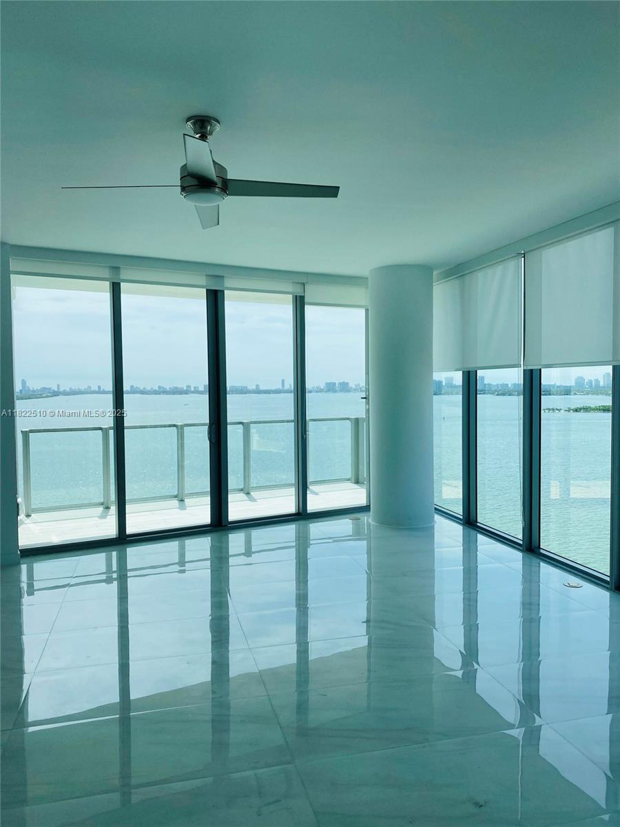 A room with white marble floors, a ceiling fan, and floor-to-ceiling windows overlooking the water — 2900 NE 7th Ave # 1407, Miami FL 33137, MIAMI, FL