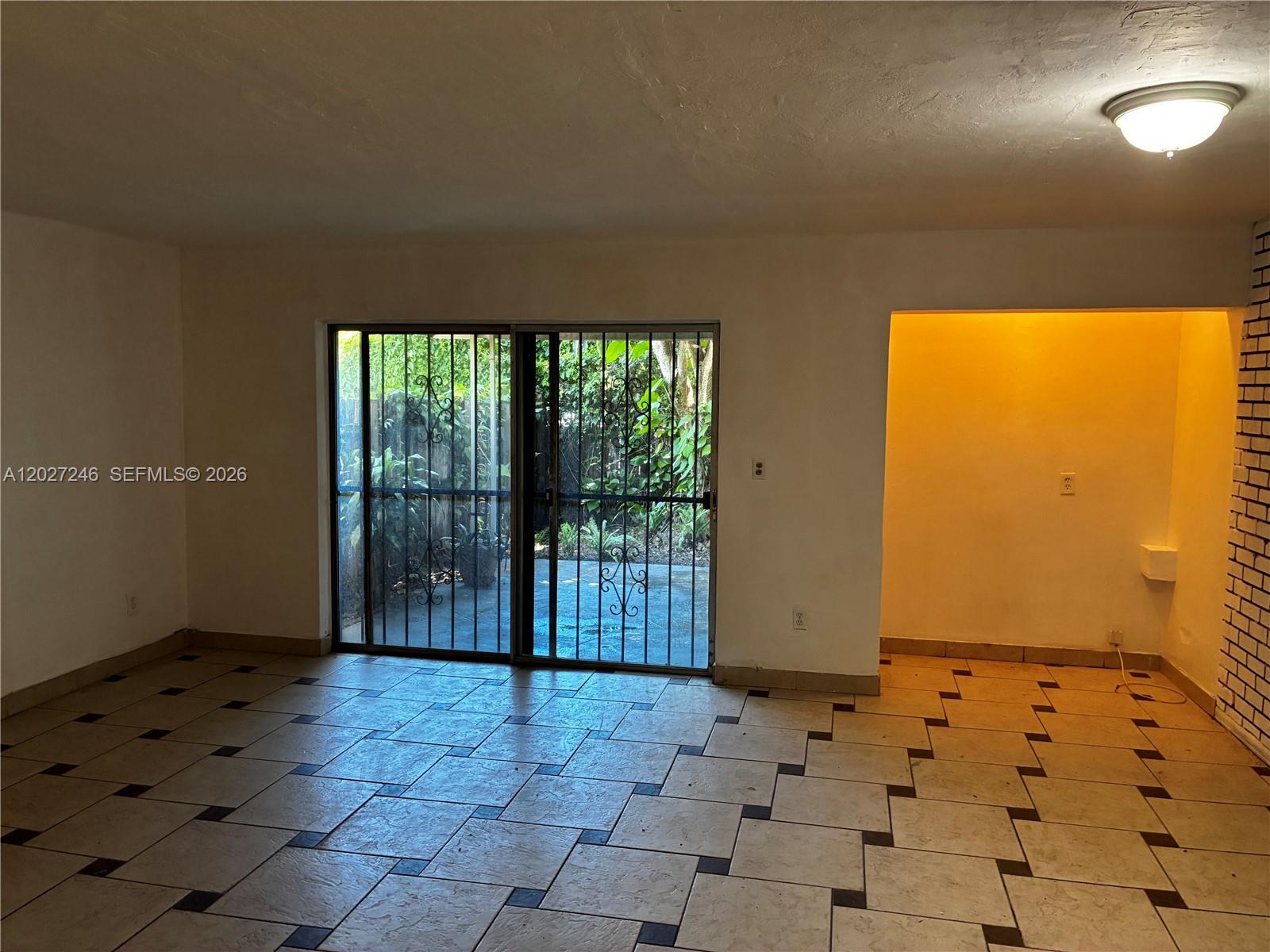A room with tiled flooring, a sliding glass door with security bars, and an alcove — 13509 NE 24th Pl, North Miami FL 33181, NORTH MIAMI, FL