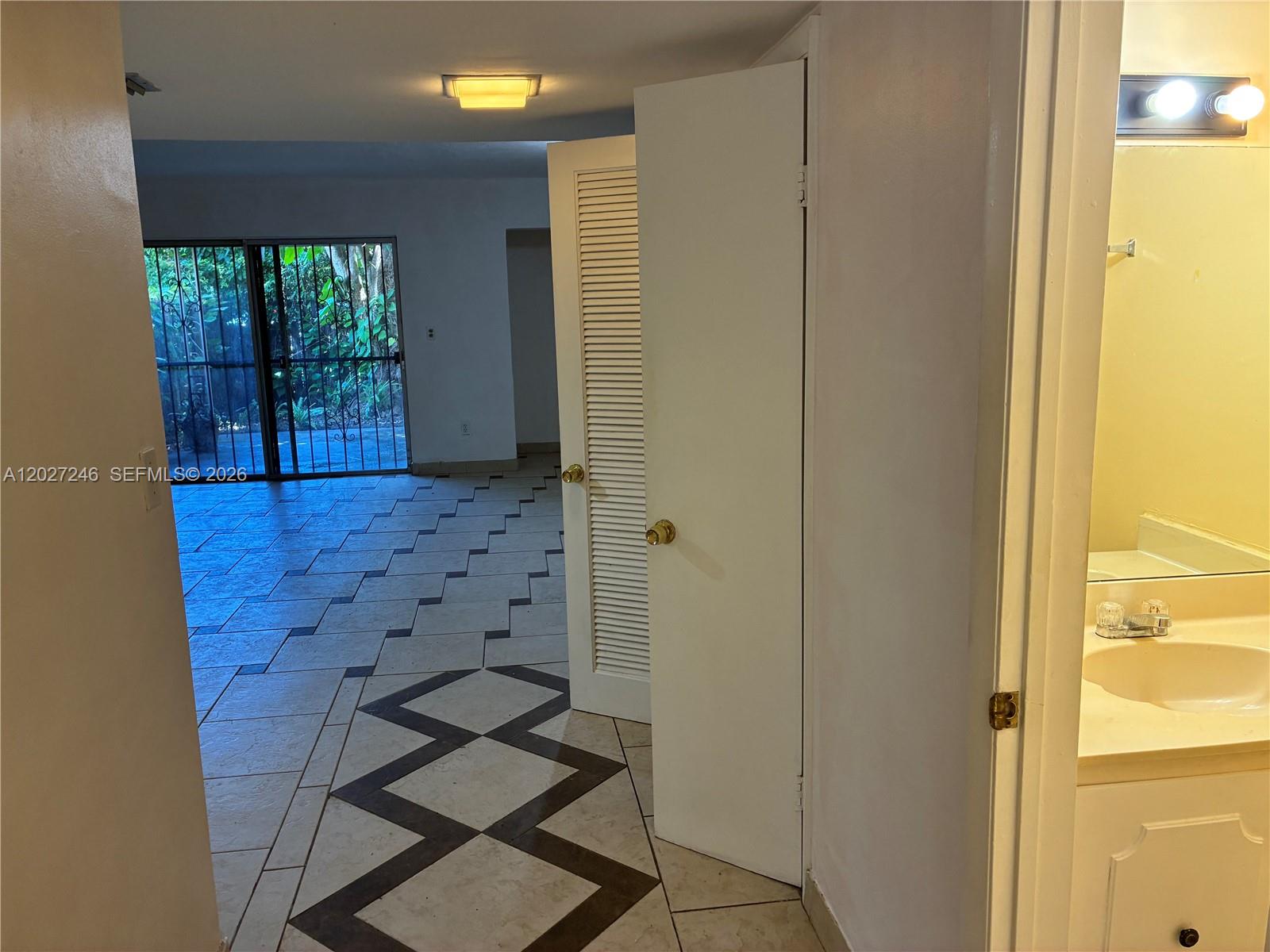 A tiled living area with a sliding glass door leads to a view of greenery — 13509 NE 24th Pl, North Miami FL 33181, NORTH MIAMI, FL