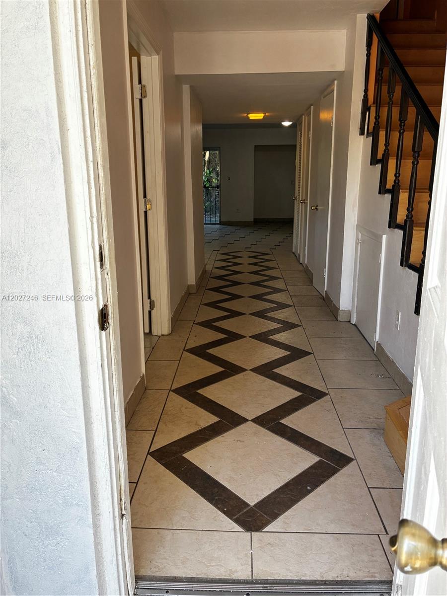 A hallway features diamond-patterned tile flooring and a staircase with a dark wooden railing — 13509 NE 24th Pl, North Miami FL 33181, NORTH MIAMI, FL