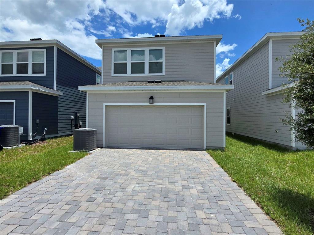 The exterior of a two-story house features a paved driveway, a garage, and light-colored siding — 4346 BENTGRASS BEND, ST CLOUD, FL