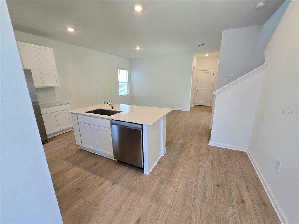 A kitchen with white cabinets, a center island, and light wood-look flooring — 4346 BENTGRASS BEND, ST CLOUD, FL