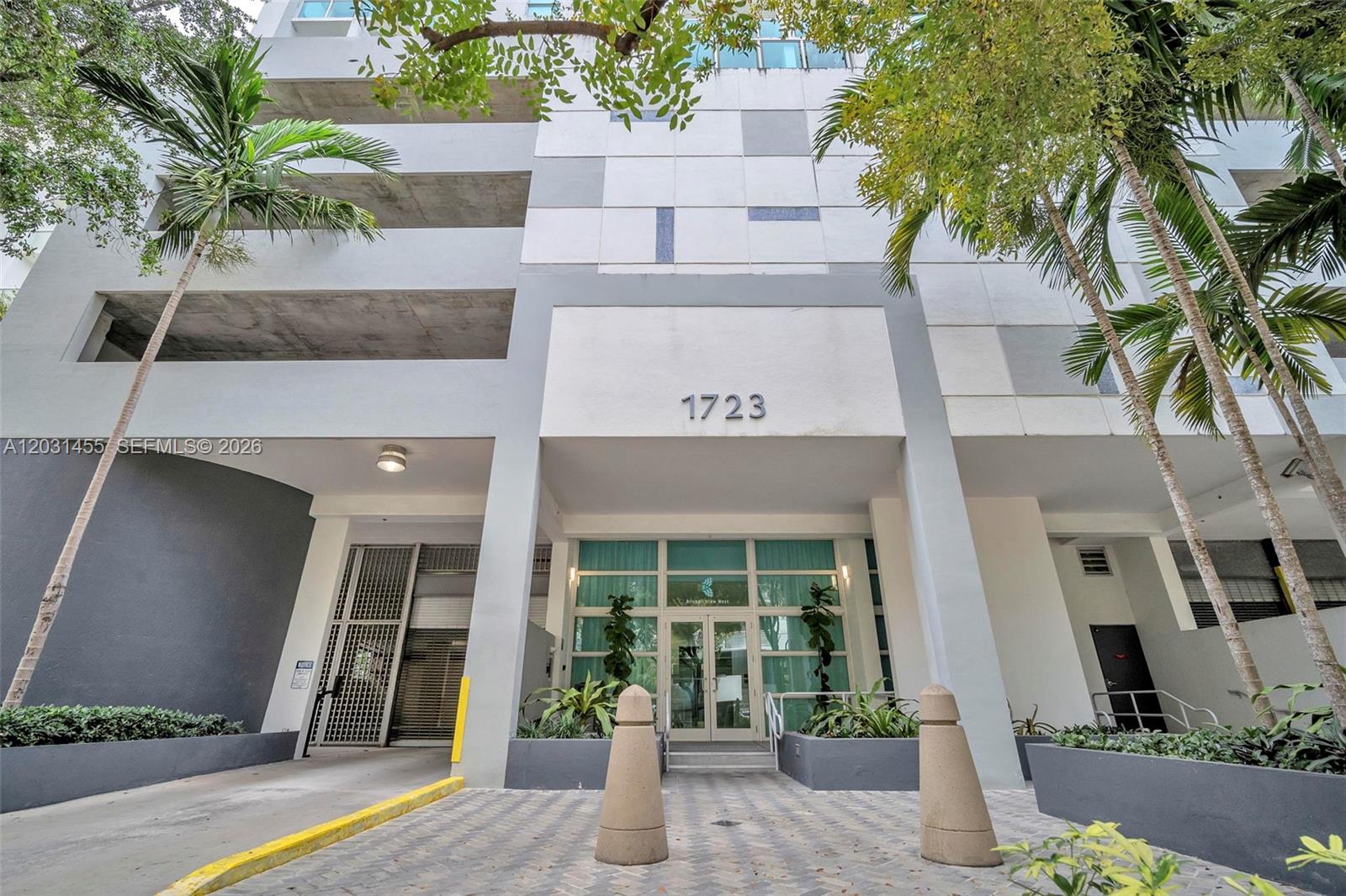 The exterior of a modern multi-story building features a glass entrance and concrete parking levels — 1723 SW 2nd Ave # 1001, Miami FL 33129, MIAMI, FL