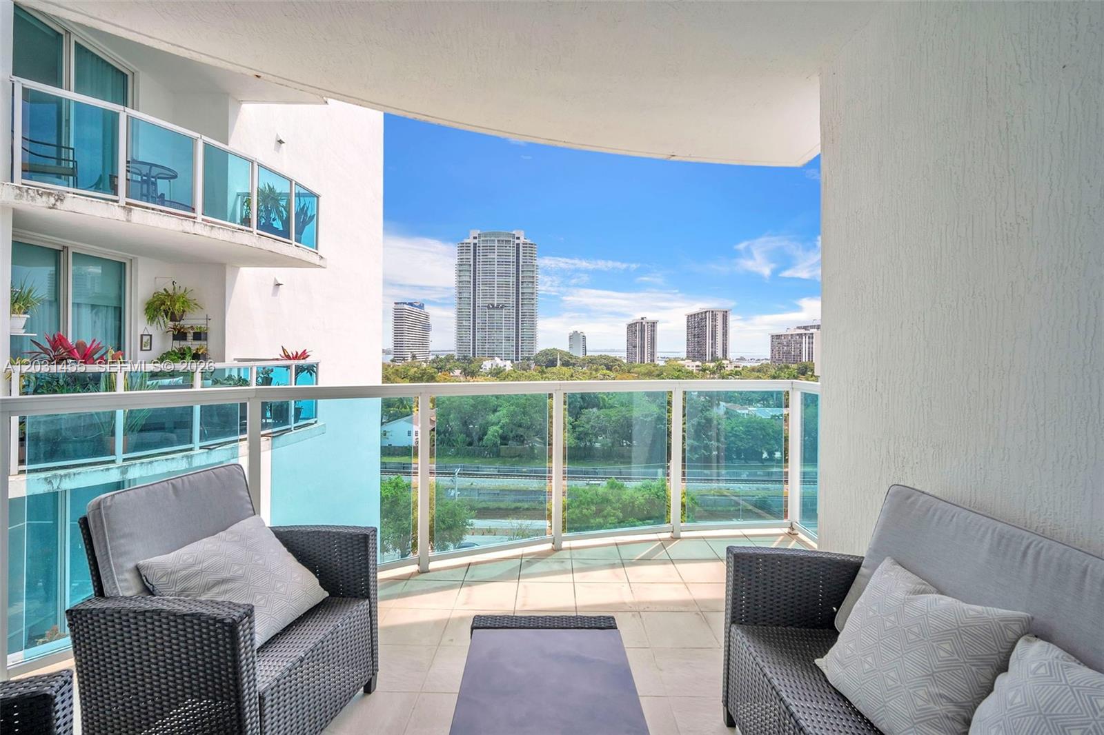 A balcony with outdoor furniture overlooks a city skyline and a green landscape — 1723 SW 2nd Ave # 1001, Miami FL 33129, MIAMI, FL