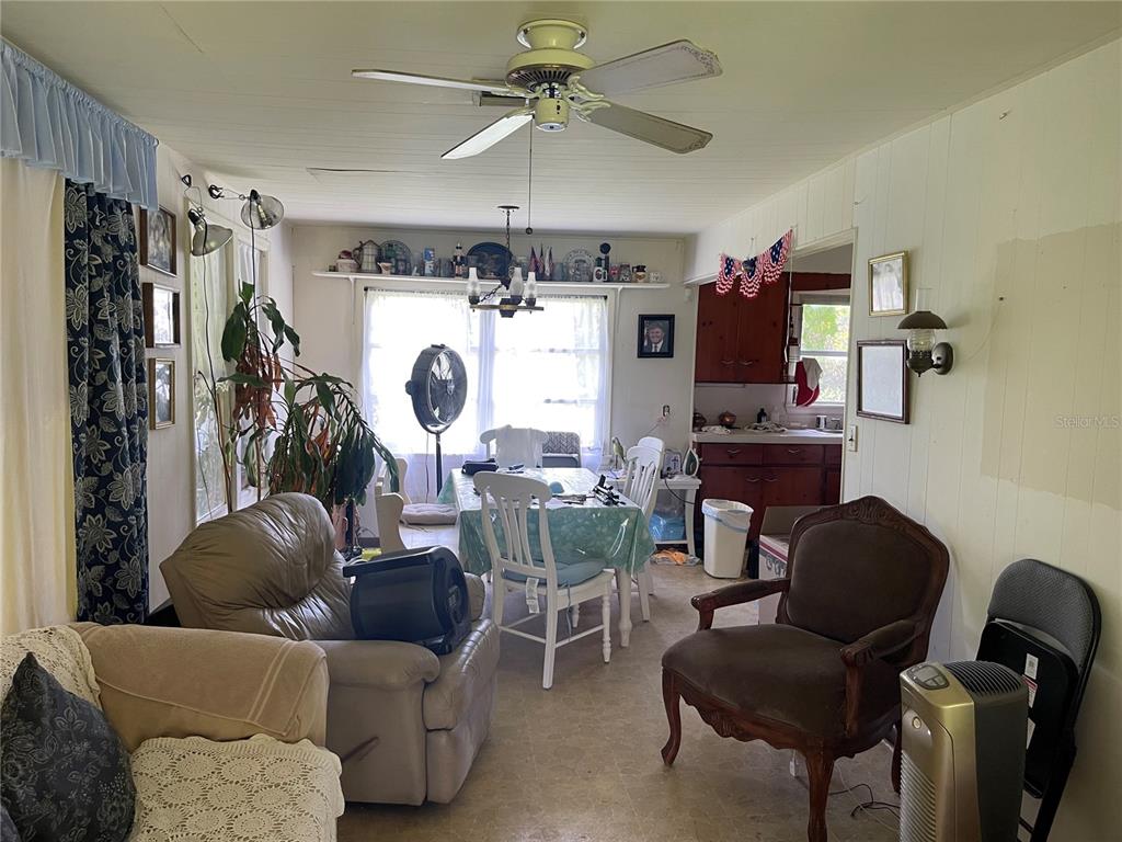 A living and dining area features a ceiling fan, white paneled walls, and wood cabinetry — 809 W PIPKIN ROAD, LAKELAND, FL