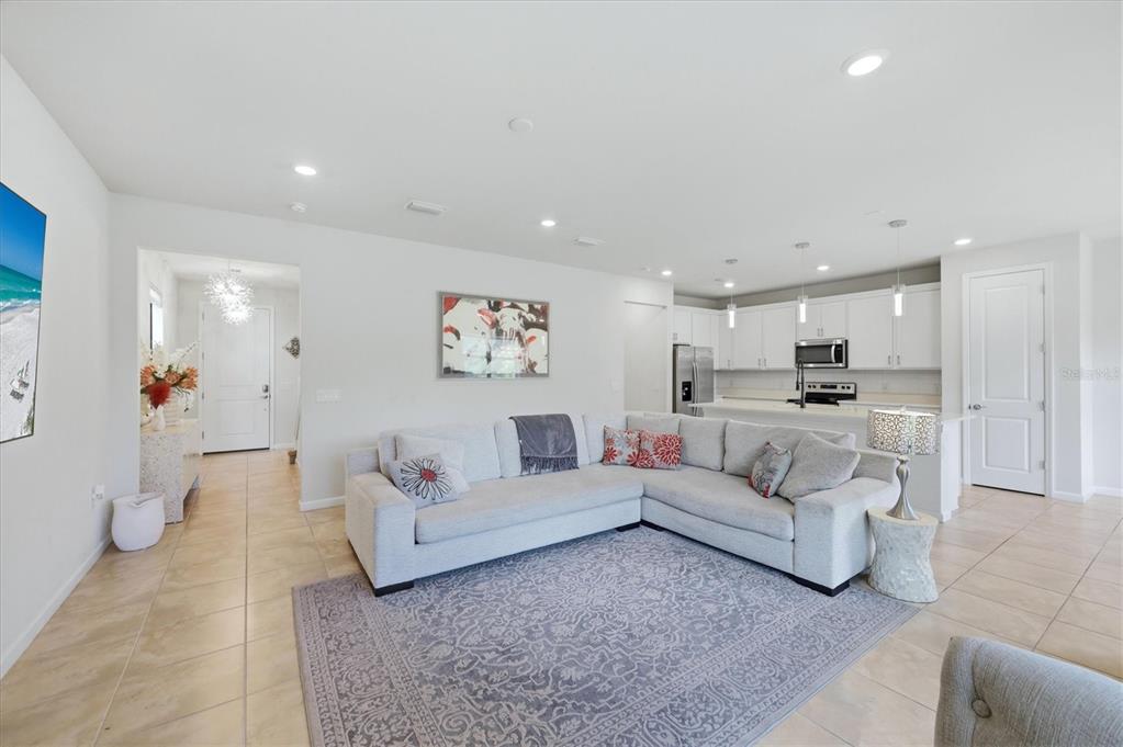 A living room with a sectional sofa, area rug, and an open kitchen in back — 6126 BLUESTAR COURT, LAKEWOOD RANCH, FL