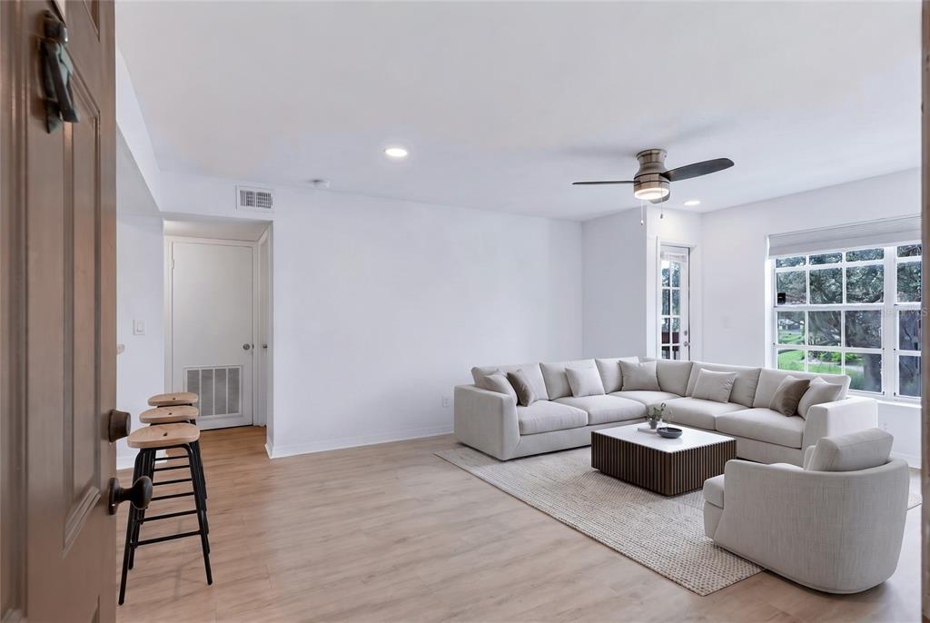 A living room with light wood floors, a sectional sofa, and a ceiling fan — 10200 GANDY BOULEVARD N UNIT 1205, ST PETERSBURG, FL