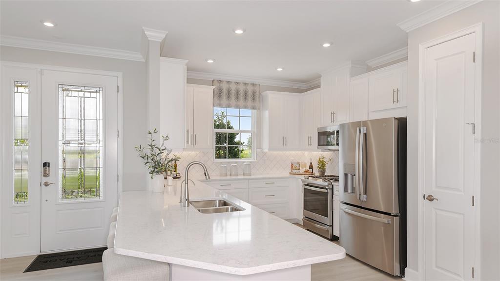 A modern kitchen features white cabinetry, stainless steel appliances, and a large quartz-topped island — 10251 MORNING MIST LANE, SARASOTA, FL