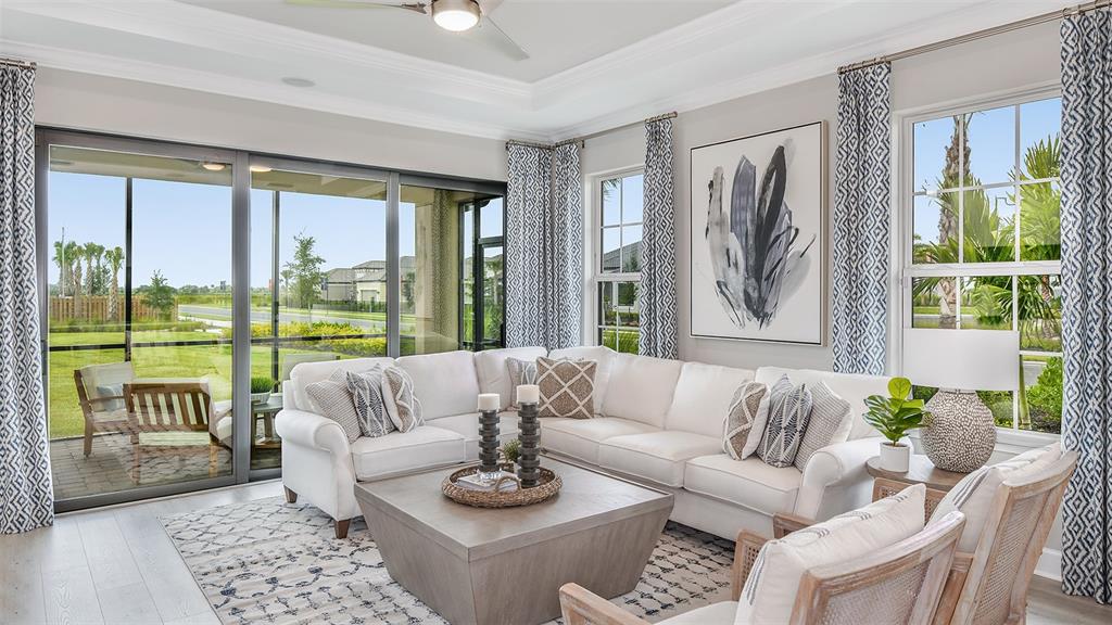 A living room features a white sectional sofa, a square coffee table, and large windows — 10251 MORNING MIST LANE, SARASOTA, FL