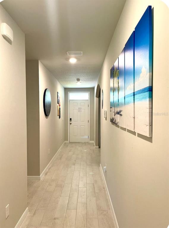 A hallway with light wood-look tile flooring leads to a white front door — 25336 DEEP CREEK BOULEVARD, PUNTA GORDA, FL