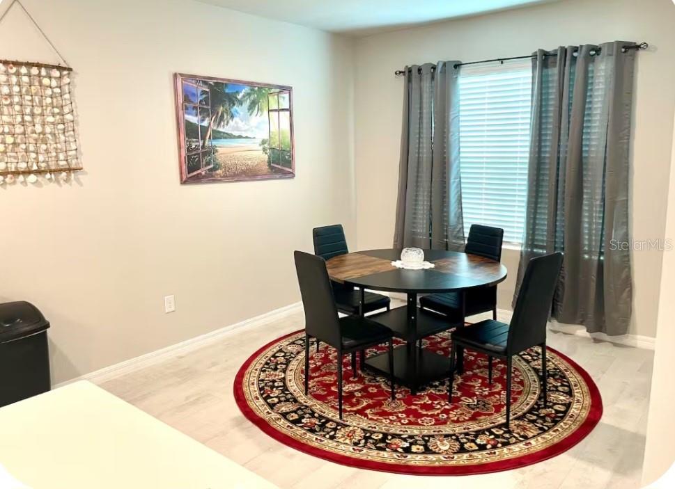 A dining area features a round table with four chairs on a circular red rug — 25336 DEEP CREEK BOULEVARD, PUNTA GORDA, FL