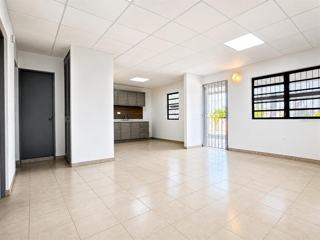 An open-plan room features light tile flooring, a small kitchenette, and a security-barred door — #1 ST. URB. VILLA ARRIETA 2ND FLOOR UNIT C-51, BAYAMON, PR