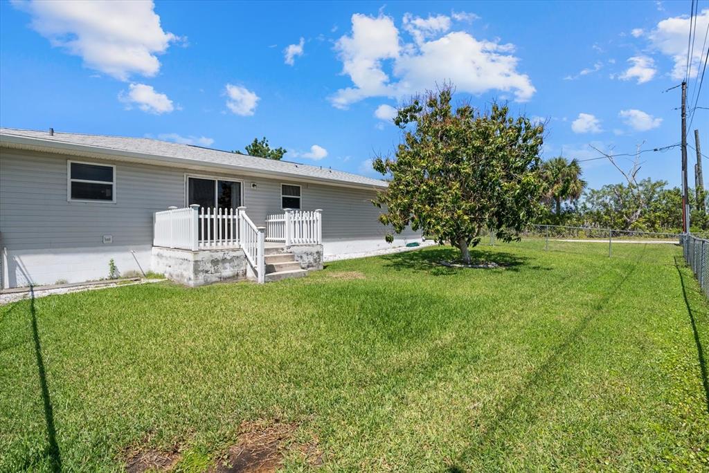 A gray house with a white deck and stairs sits in a grassy backyard — 2600 CHARLENE STREET, PUNTA GORDA, FL