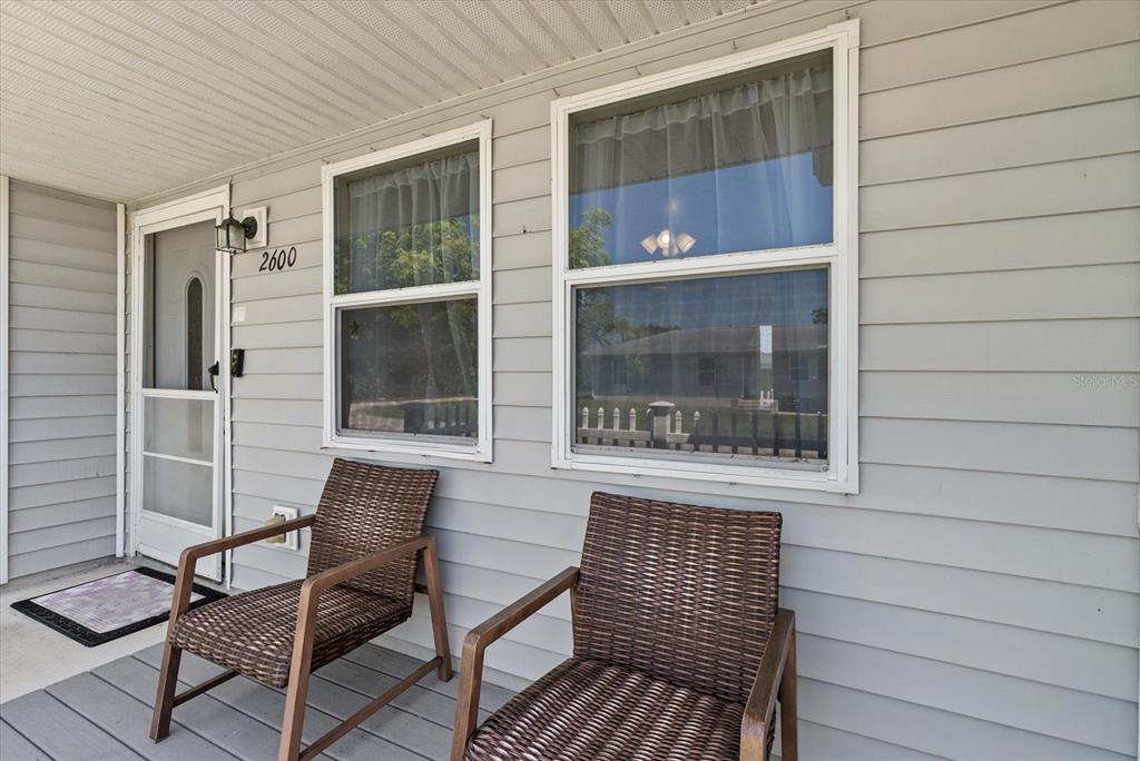 A covered front porch features two wicker chairs, light gray siding, and a white door — 2600 CHARLENE STREET, PUNTA GORDA, FL