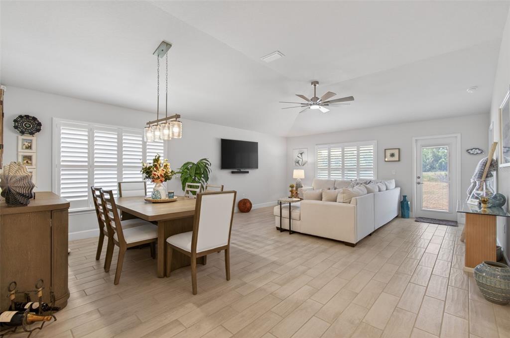 An open-concept living and dining area features light tile flooring, white walls, and a ceiling fan — 25013 SW 24TH PLACE, NEWBERRY, FL