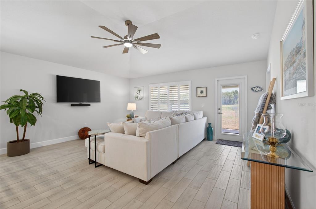 A living room features a white sectional sofa, a ceiling fan, and light wood-look tile flooring — 25013 SW 24TH PLACE, NEWBERRY, FL