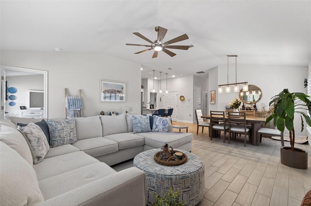 A spacious open-concept living and dining area features light gray walls, tile flooring, and furniture — 25013 SW 24TH PLACE, NEWBERRY, FL