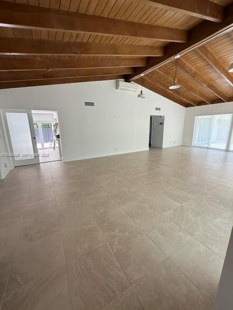 A spacious room features light tile flooring and a vaulted wood-paneled ceiling — 1047 NE 84th St, Miami FL 33138, MIAMI, FL
