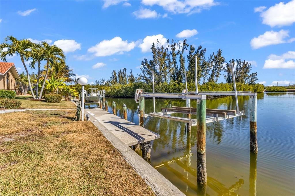 A concrete boat dock with a mechanical lift extends into a canal near a house — 3518 TERIN COURT, PUNTA GORDA, FL