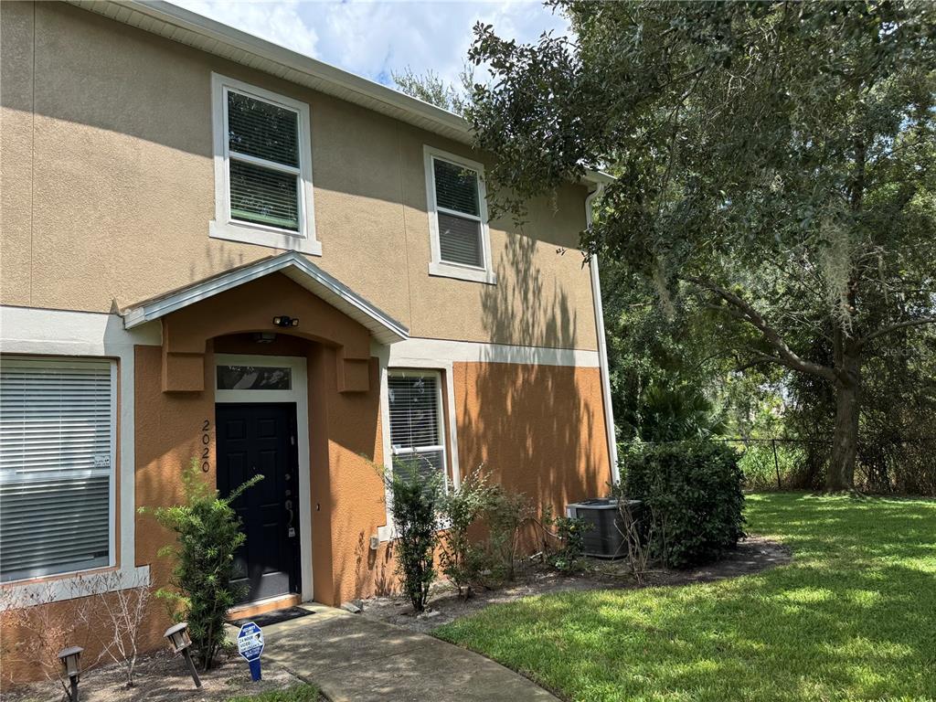 A two-story tan and orange stucco townhouse with a black front door and lawn — 2020 SAN JACINTO CIRCLE UNIT 200, SANFORD, FL