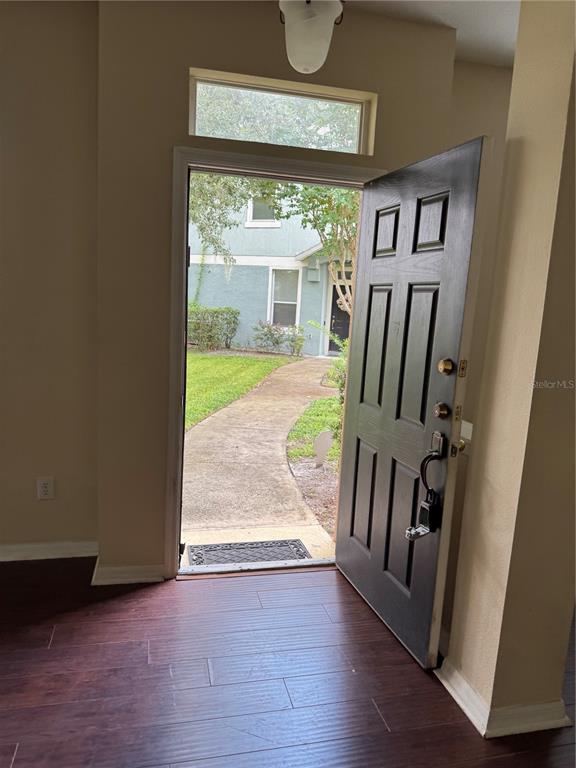 An open front door reveals a concrete walkway leading to a neighboring building exterior — 2020 SAN JACINTO CIRCLE UNIT 200, SANFORD, FL