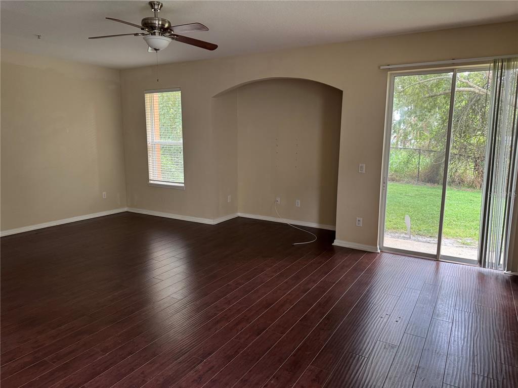 An empty living room with dark wood flooring, a ceiling fan, and a sliding glass door — 2020 SAN JACINTO CIRCLE UNIT 200, SANFORD, FL