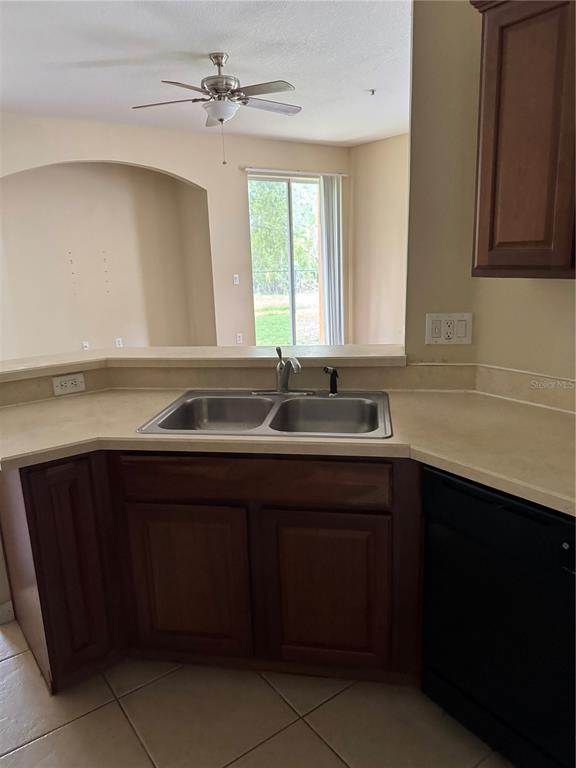 A kitchen sink area features brown cabinets, a laminate countertop, and a view of a patio — 2020 SAN JACINTO CIRCLE UNIT 200, SANFORD, FL