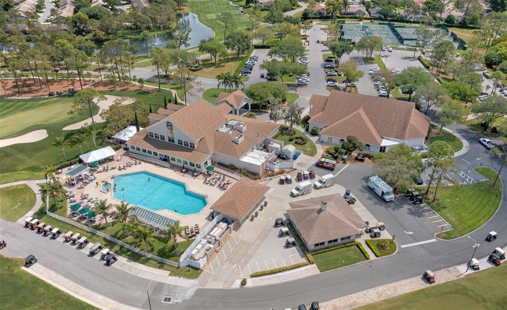 An aerial view shows a clubhouse complex with a swimming pool, parking lots, and golf course — 6409 WEDGEWOOD DRIVE, SPRING HILL, FL