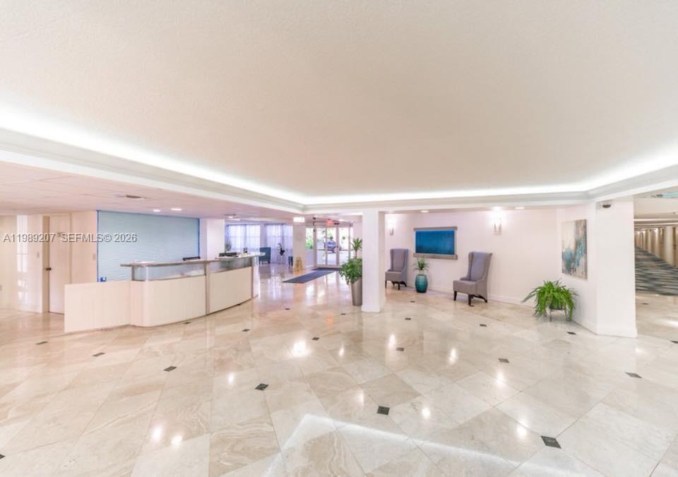 A bright, tiled lobby features a curved reception desk, seating area, and recessed ceiling lighting — 800 Parkview Dr # 222, Hallandale Beach FL 33009, HALLANDALE BEACH, FL