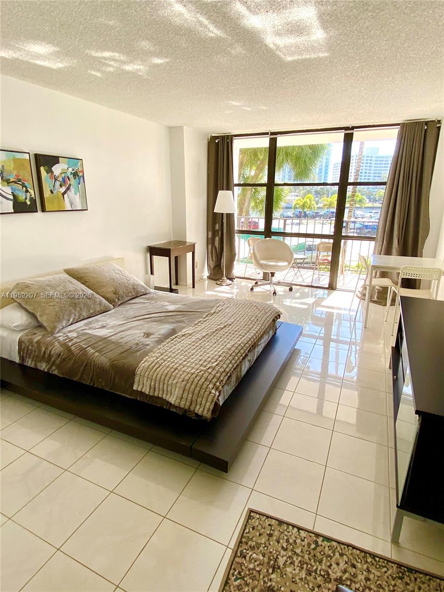 A bedroom features a platform bed, tile flooring, and a balcony with water views — 800 Parkview Dr # 222, Hallandale Beach FL 33009, HALLANDALE BEACH, FL