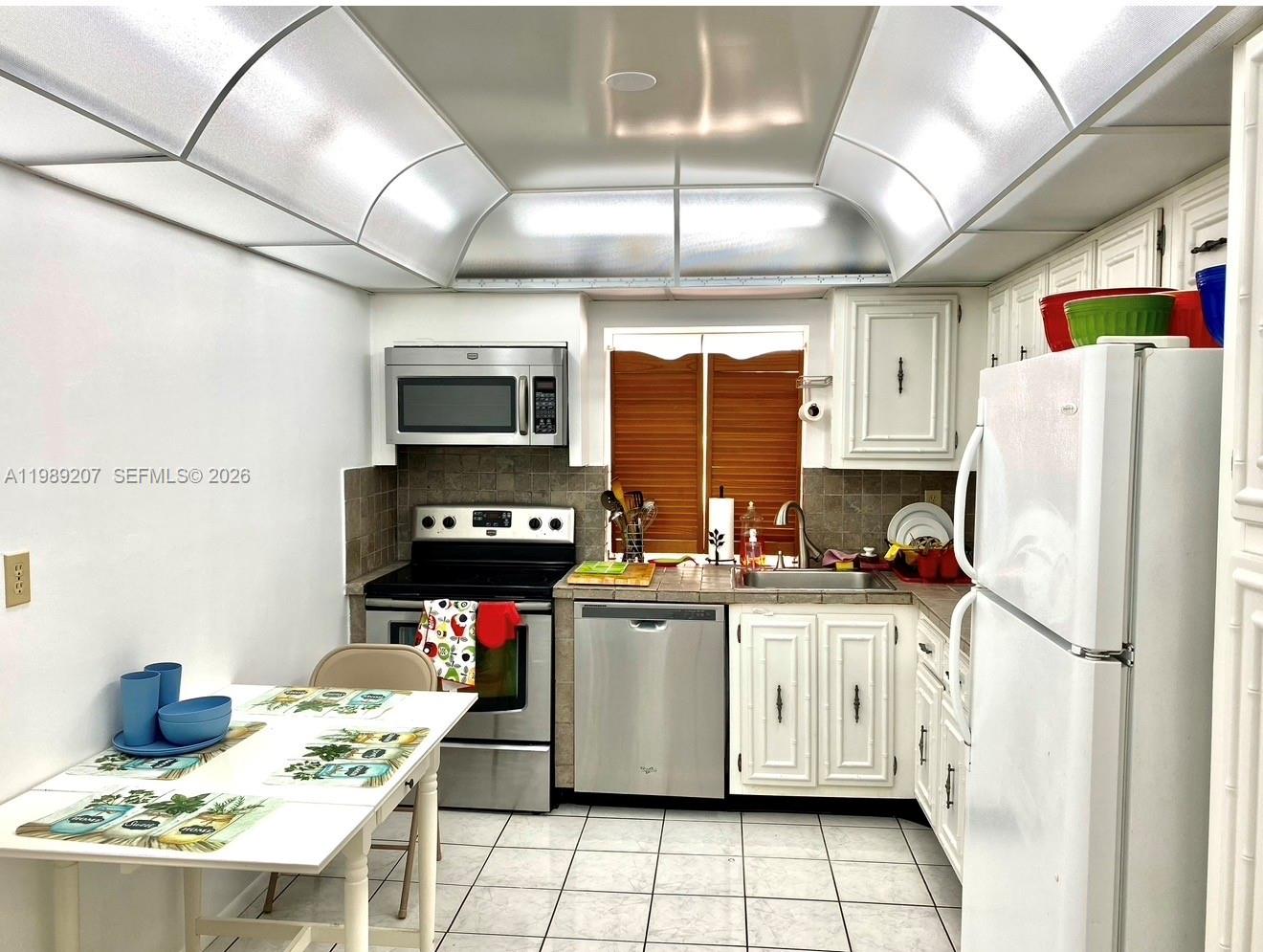 A kitchen with white cabinets, stainless steel appliances, tile flooring, and a vaulted ceiling — 800 Parkview Dr # 222, Hallandale Beach FL 33009, HALLANDALE BEACH, FL