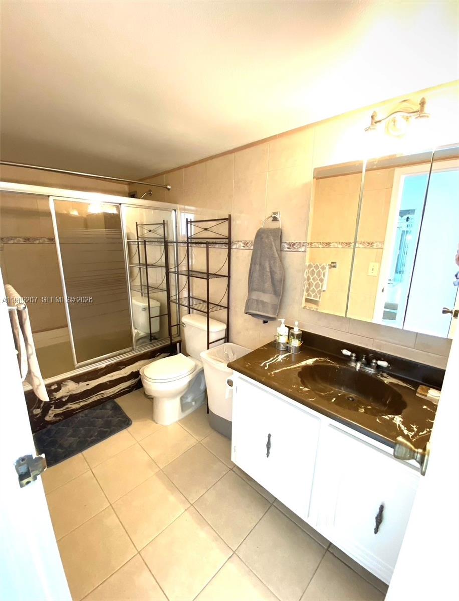 A bathroom features a vanity with a dark countertop, a toilet, and a glass-enclosed shower — 800 Parkview Dr # 222, Hallandale Beach FL 33009, HALLANDALE BEACH, FL