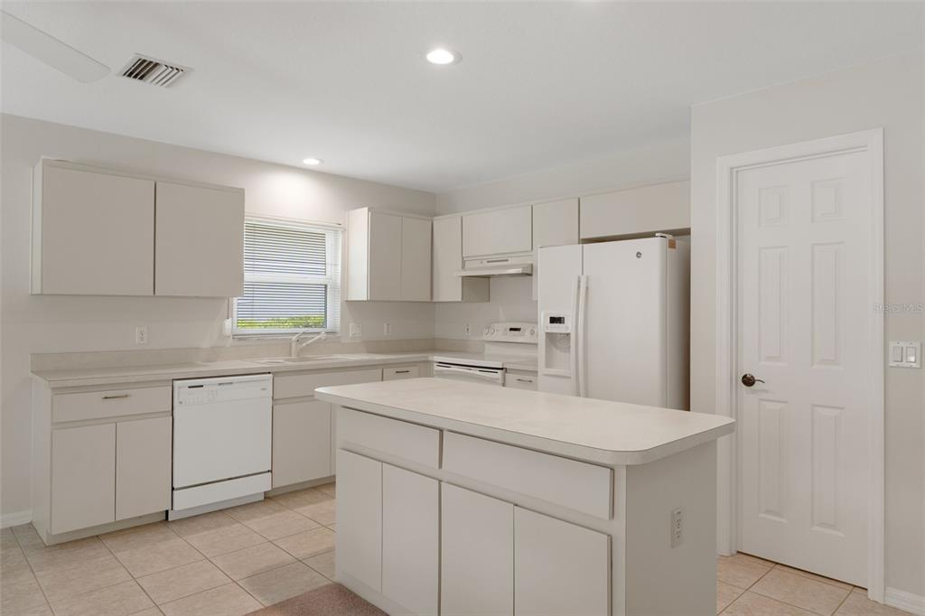 A kitchen with light-colored cabinets, white appliances, a central island, and tiled flooring — 978 W COLBERT COURT, BEVERLY HILLS, FL
