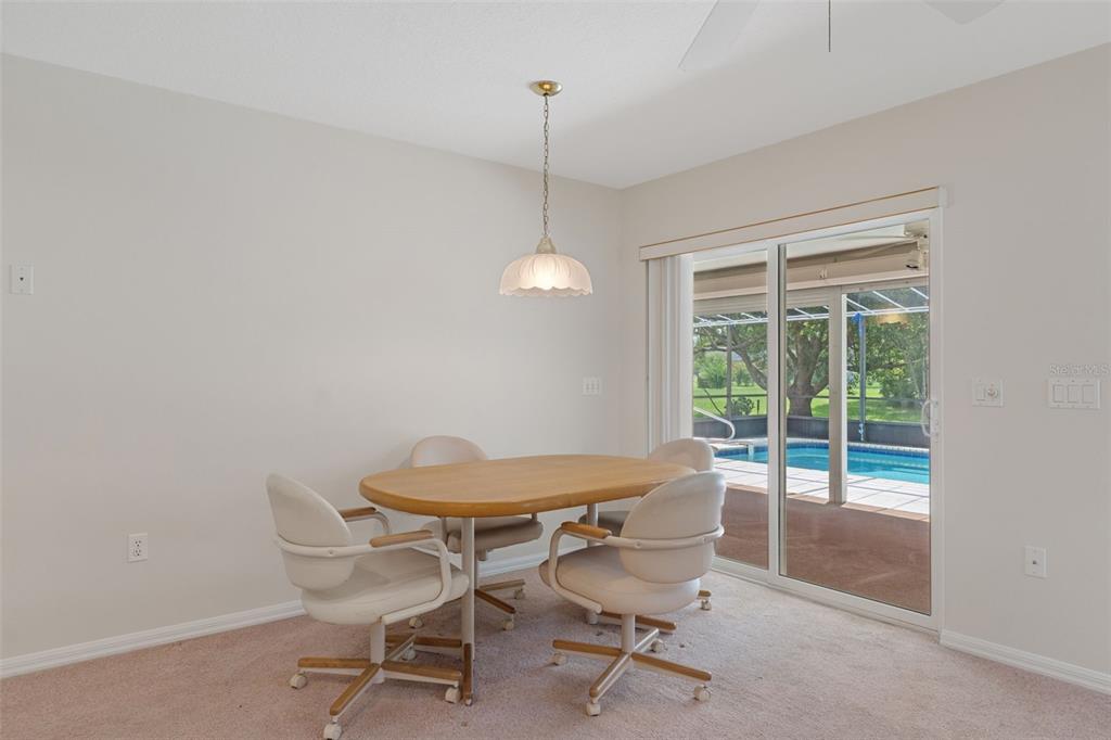 A dining area features a wooden table, four rolling chairs, a pendant light, and sliding doors — 978 W COLBERT COURT, BEVERLY HILLS, FL