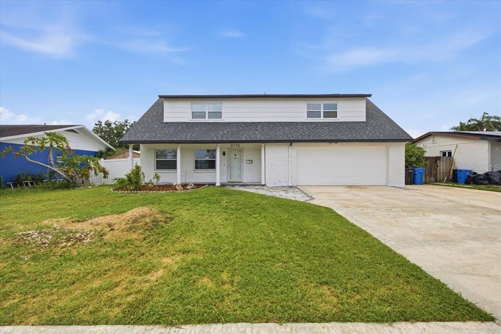 A white brick house features a paved walkway leading to a covered front porch — 4710 TRAVERTINE DRIVE, TAMPA, FL