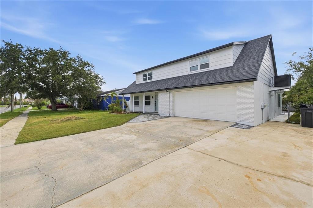 A backyard with a swimming pool, a patio with chairs, and a two-story white house — 4710 TRAVERTINE DRIVE, TAMPA, FL