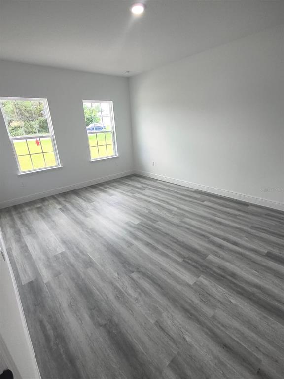An empty bedroom features white walls, two windows, and gray wood-look plank flooring — 171 MARION OAKS TRAIL, OCALA, FL