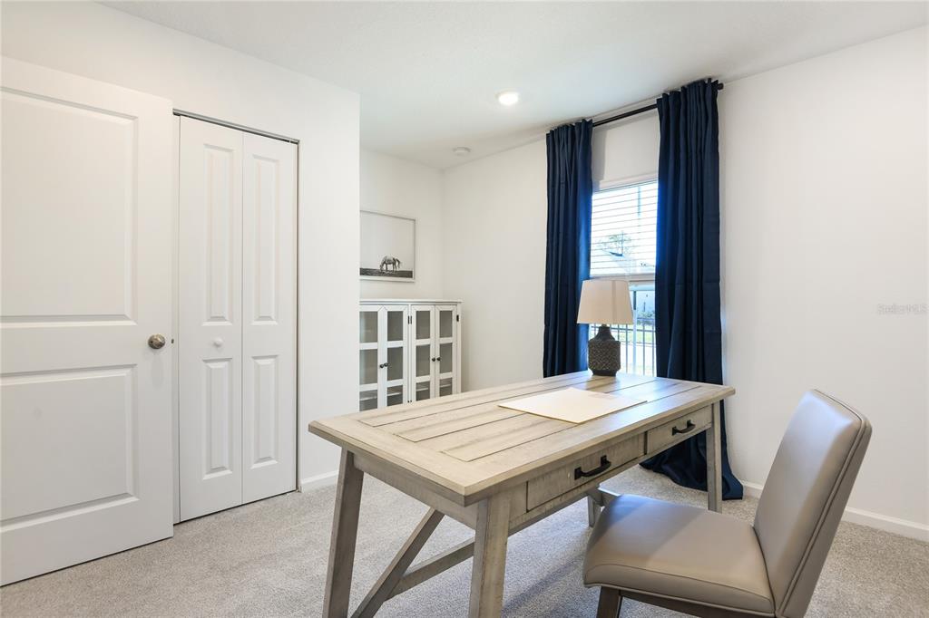 A home office features a wooden desk, a grey chair, and a white storage cabinet — 5812 LAGOON CRUISE WAY, JACKSONVILLE, FL